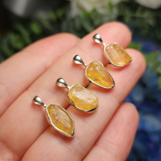May include: Four silver pendants with yellow gemstone inclusions. The pendants are all different shapes and sizes, but they are all set in silver and have a similar yellow color.