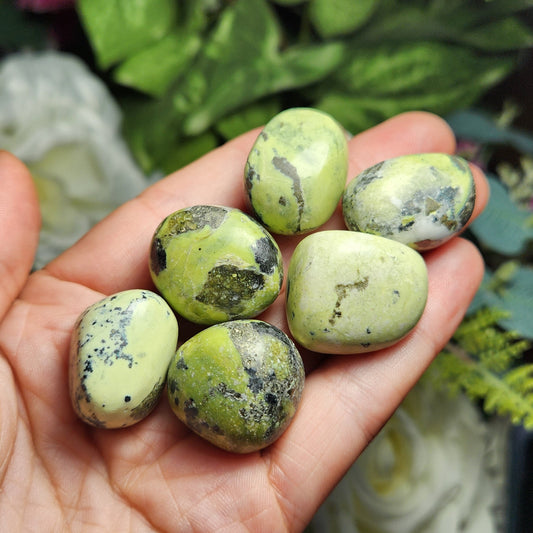 May include: A collection of six green and yellow tumbled stones. The stones have a mottled pattern and are smooth and polished.