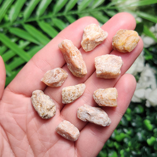 May include: A collection of sunstone rough stones.  The stones are various shades of light orange and beige, with some showing translucent qualities.  They are irregularly shaped, with rough, unpolished surfaces, and range in size. These natural sunstone crystals are perfect for jewelry making, crystal healing, or adding to a rock collection.