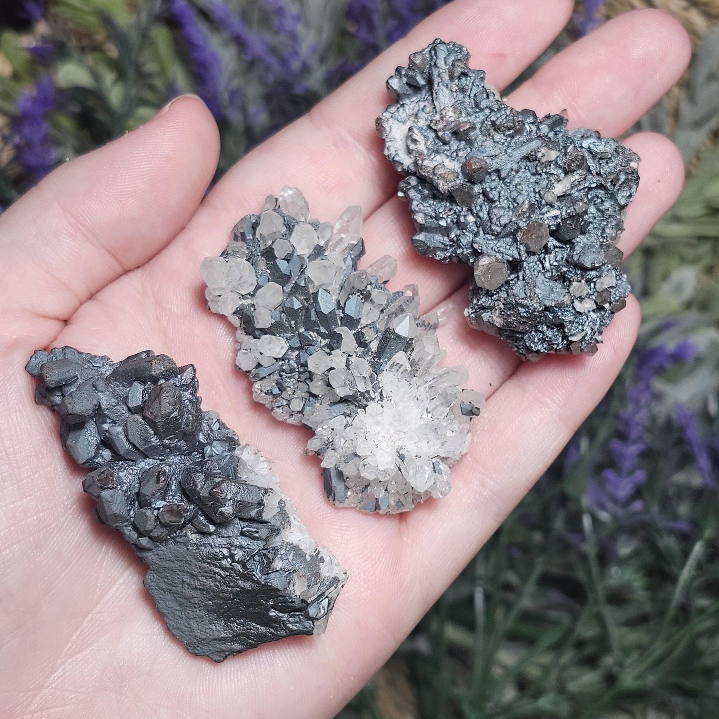May include: Three specimens of quartz crystals combined with dark gray metallic minerals. The crystals exhibit a cluster formation, with the clear quartz points interspersed among the darker mineral matrix. The color contrast is striking, creating an interesting visual texture. These unique mineral specimens would be ideal for collectors or those interested in metaphysical properties.