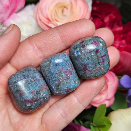 May include: Three tumbled stones with a blue and green base and red and pink flecks. The stones are smooth and polished.