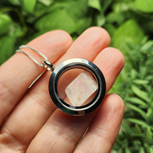 May include: A silver locket necklace with a clear glass insert containing a small, white, rectangular crystal.
