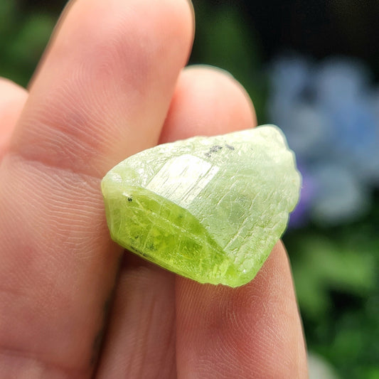 May include: A vibrant green crystal, exhibiting a translucent quality with visible internal striations.  The crystal displays a unique, multifaceted form, showcasing sharp edges and a slightly rough texture. Its color is consistent throughout, with subtle variations in tone.  The overall shape is irregular, resembling a fragmented shard with a slightly curved surface. This specimen is a striking example of a naturally formed crystal.