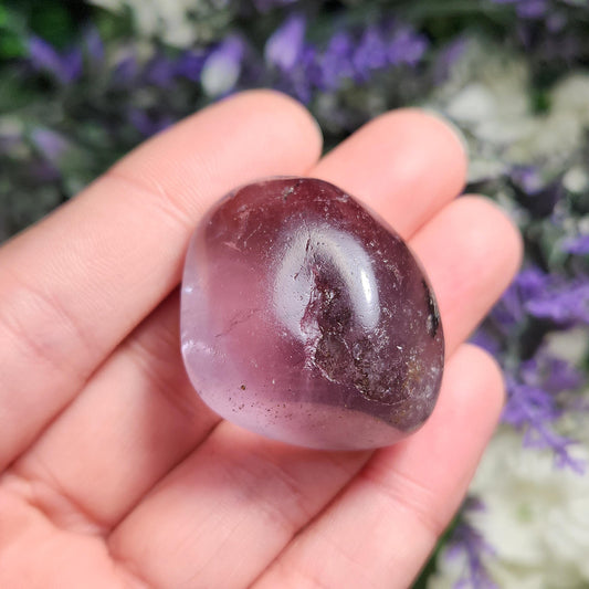 May include: A smooth, polished purple amethyst crystal with a light purple hue. The crystal is heart shaped and has a glossy finish.