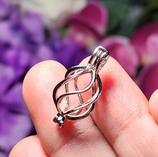 May include: A silver metal cage pendant with a swirl design. The cage is open at the top and has a loop for attaching to a chain.