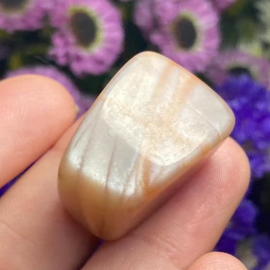 May include: A smooth, light brown and white gemstone with a pearlescent sheen.