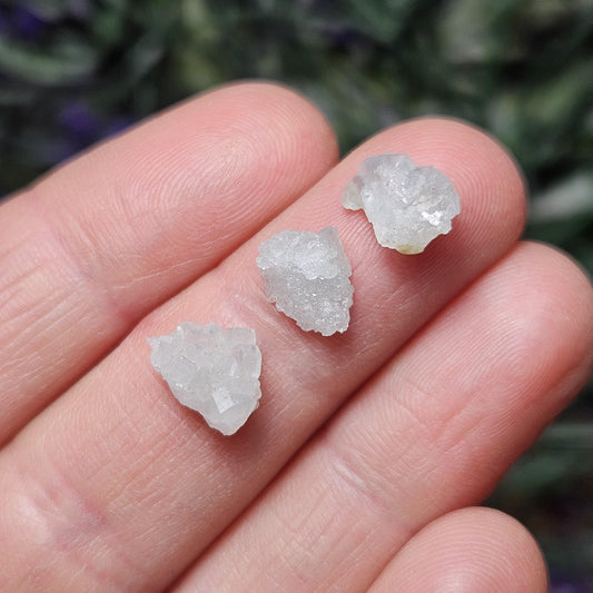 May include: Three small, opaque, white quartz crystal clusters.  The crystals have a rough, naturally formed texture and exhibit a subtle, sparkly quality.  They are showcased against a neutral background, highlighting their unique formations and delicate crystalline structures. These raw, uncut specimens are ideal for crystal healing, collection, or decorative purposes.