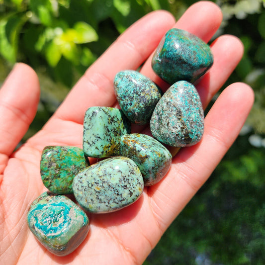 May include: A collection of eight green and black tumbled stones. The stones are smooth and have a variety of patterns and textures.
