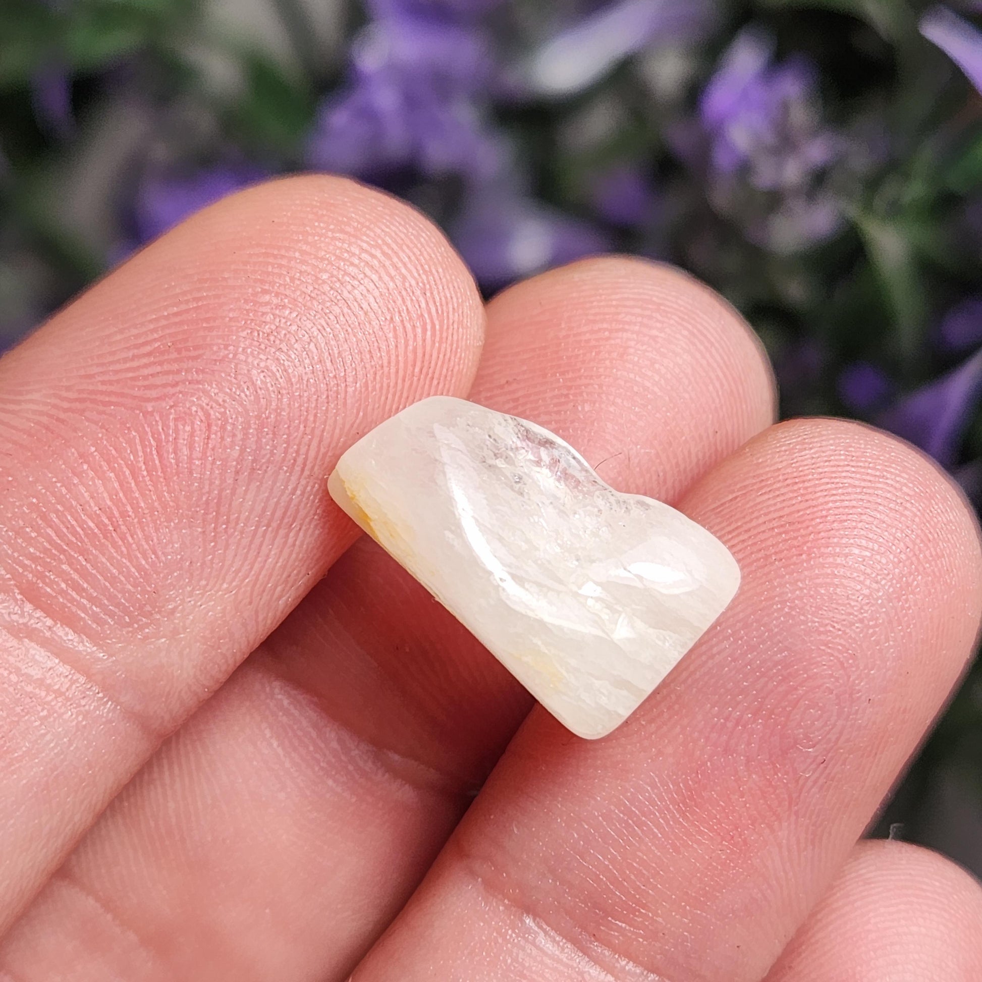 May include: A white, translucent, irregularly shaped gemstone with a smooth, polished surface.