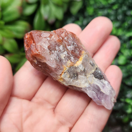 May include: A raw amethyst crystal with a red and clear quartz point. The crystal has a natural, rough texture and is a beautiful example of the natural beauty of crystals.