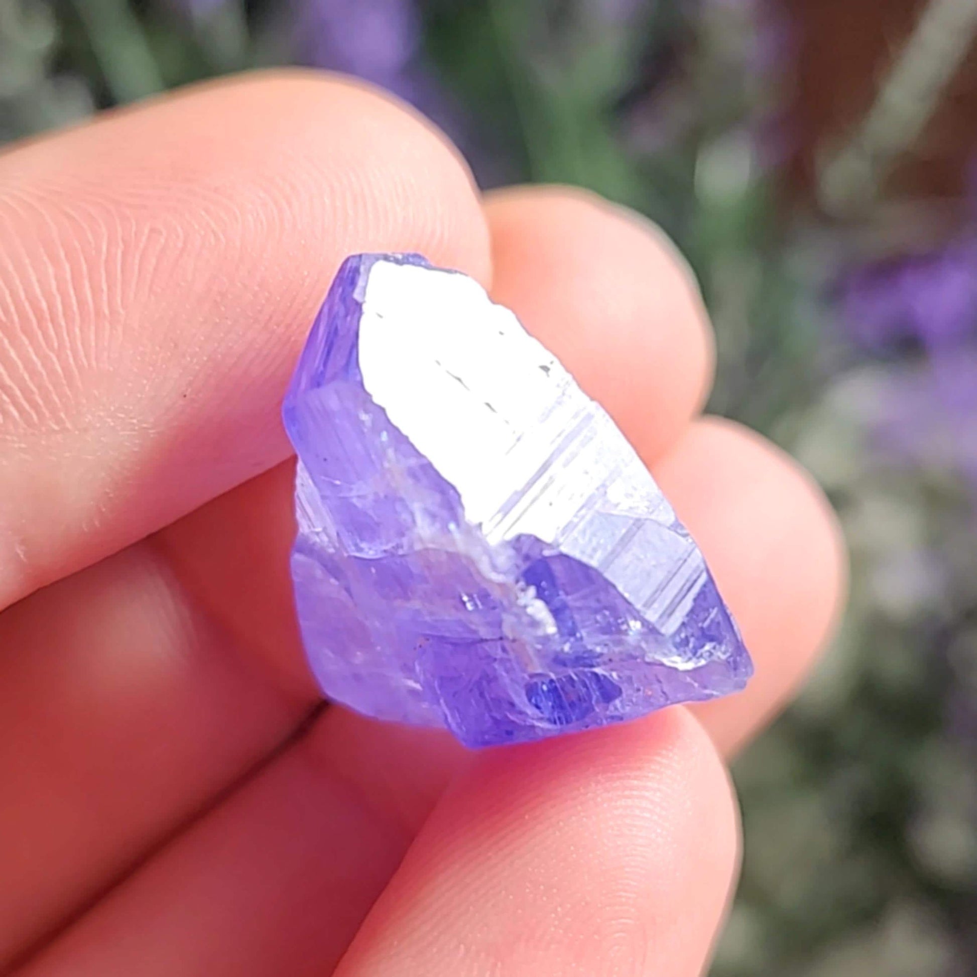 May include: A deep purple, faceted, rough-cut crystal with a pointed tip. The crystal is translucent and has a slight sheen.