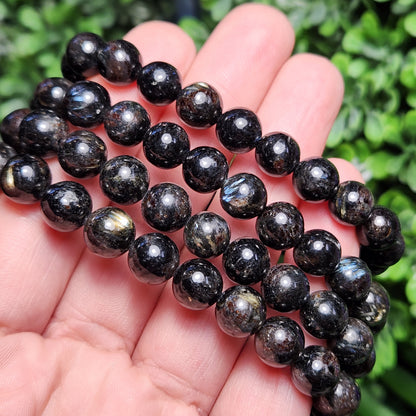 May include: A black beaded bracelet with iridescent shimmer. The beads are round and have a smooth, polished finish.